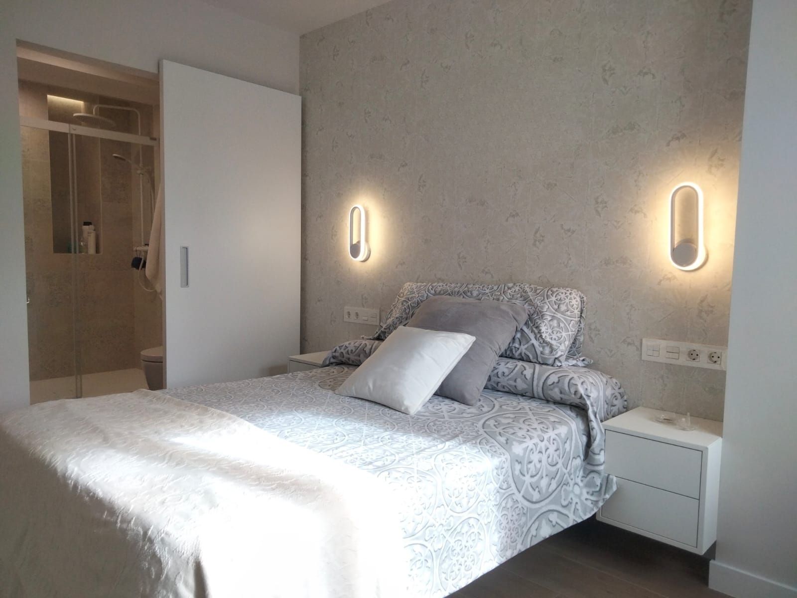 Un dormitorio con cama, mesita de noche y puerta corrediza.