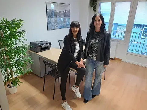 Dos mujeres están paradas una al lado de la otra en una oficina.