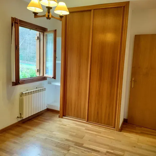 Una habitación con un armario de madera y una ventana.