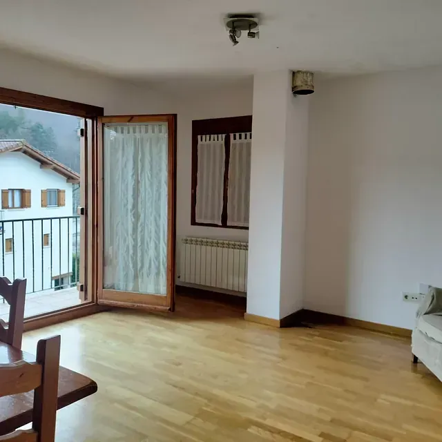 Una sala de estar con pisos de madera y un balcón.