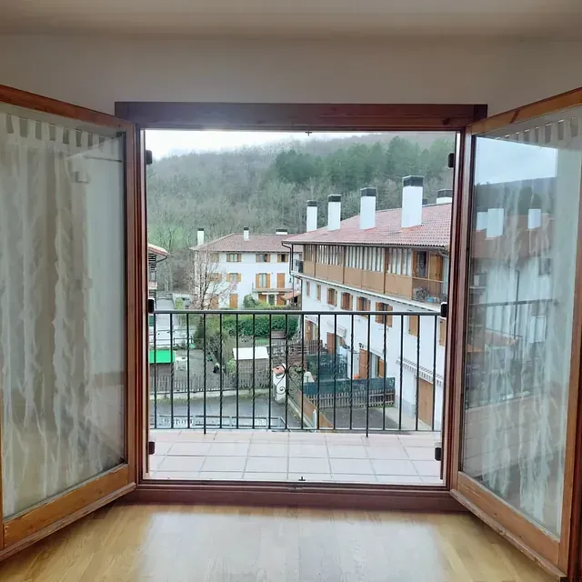 Una ventana abierta con vista a un balcón y edificios.