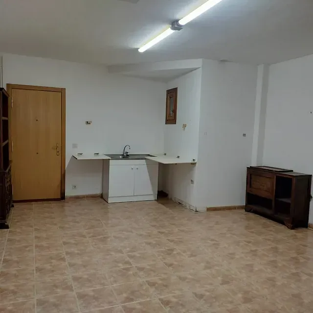 Una habitación vacía con un lavabo, armarios y una puerta.