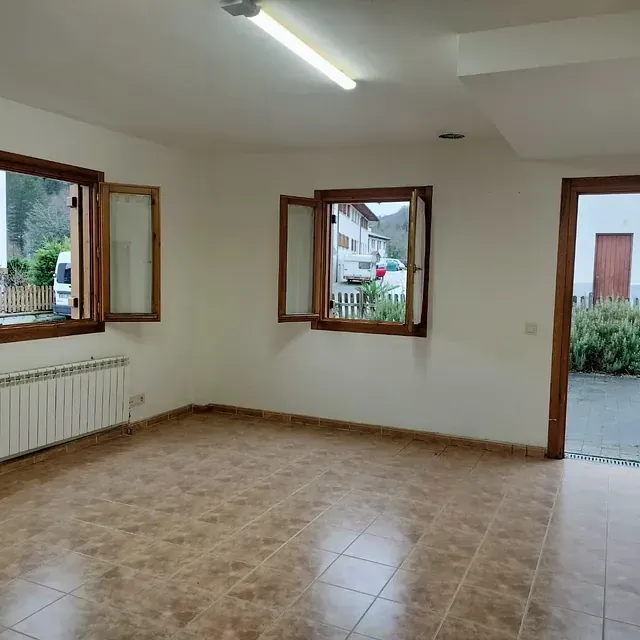 Una habitación vacía con suelo de baldosas y dos ventanas.