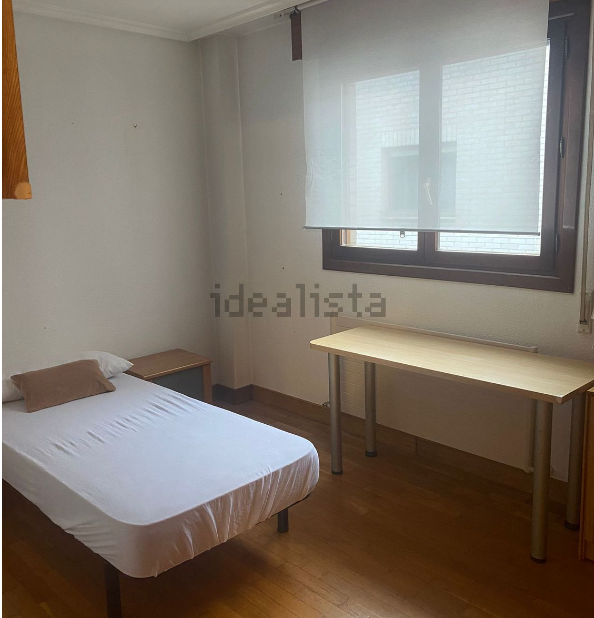 Un dormitorio con una cama y un escritorio con idealista escrito en la pared