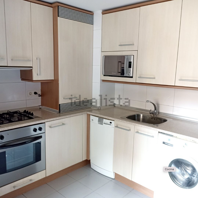 Una cocina con electrodomésticos de acero inoxidable y gabinetes blancos tiene la palabra idealista en la parte inferior derecha.