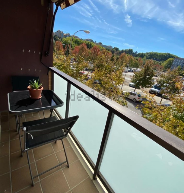 Un balcón con una mesa y sillas y una planta en maceta.