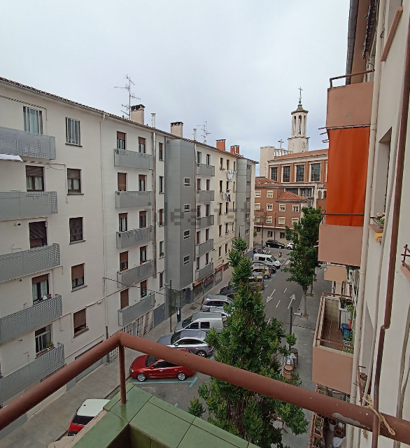 Una vista de una calle de la ciudad desde un balcón que dice 'alquiler'.