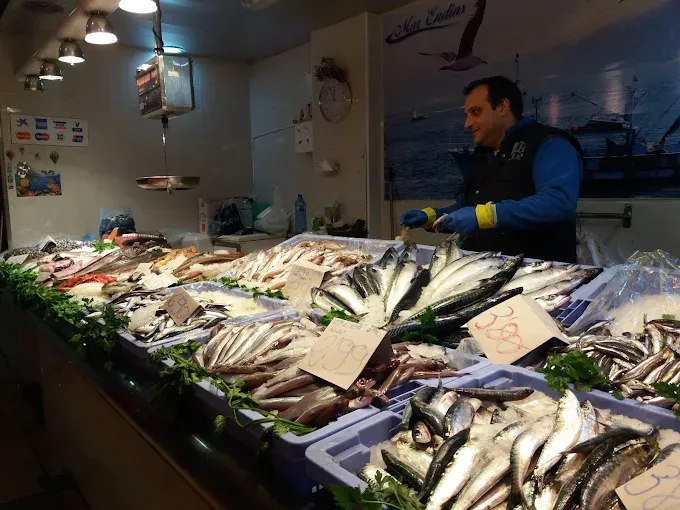 Un hombre está parado frente a una mesa llena de pescado.