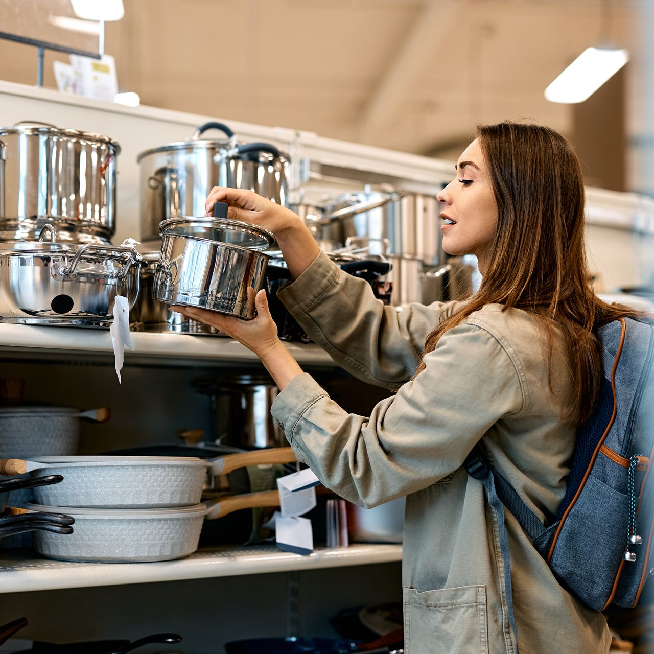 Une femme choisissant une casserole dans un magasin d'ustensiles de cuisine.