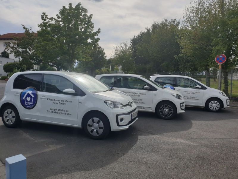 Drei weiße Firmenwagen parkten auf einem Parkplatz neben Bäumen unter einem bewölkten Himmel