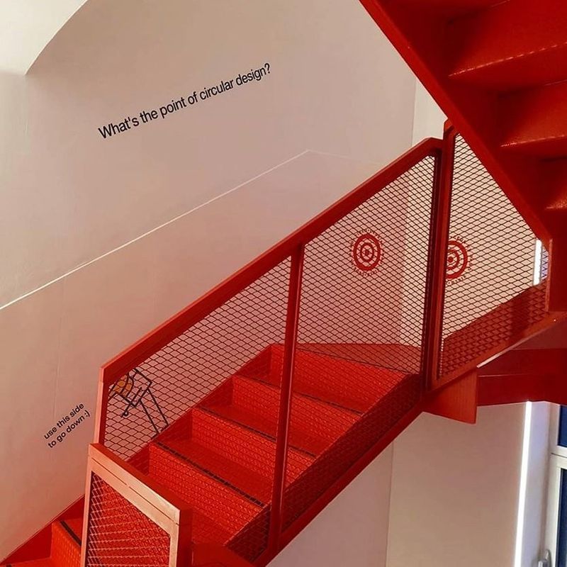 Una escalera roja con un cartel que dice ¿cuál es el sentido del diseño circular?