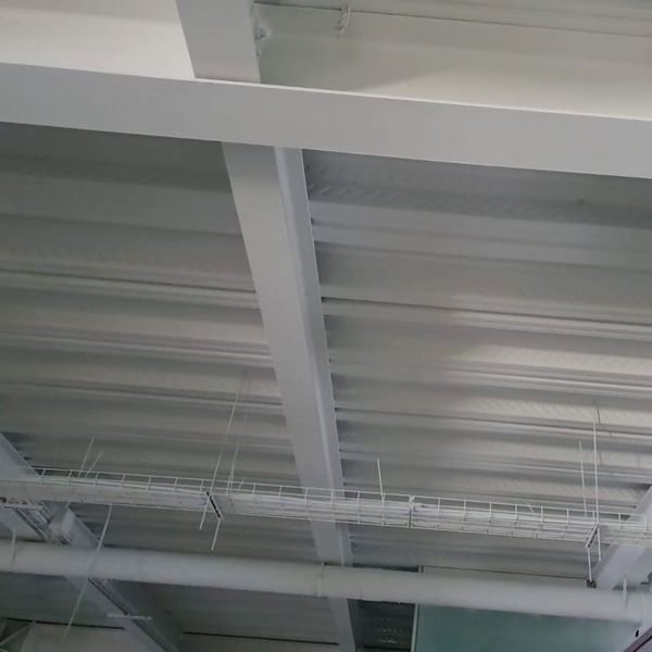 El techo de un edificio está pintado de blanco y tiene muchos tubos colgando de él.