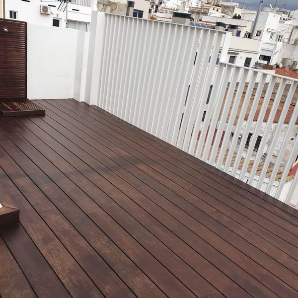 Un balcón con terraza de madera y barandilla blanca.