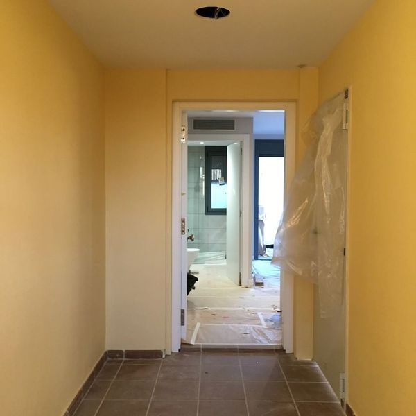 Un pasillo con paredes amarillas que conduce a un baño.