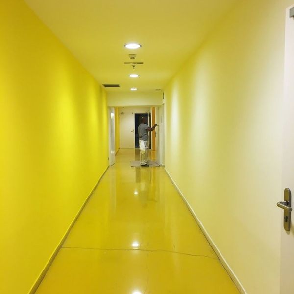 Un largo pasillo con paredes amarillas y pisos amarillos.