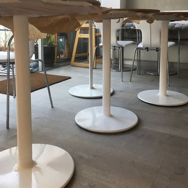 Una habitación con mesas y sillas con bases blancas.