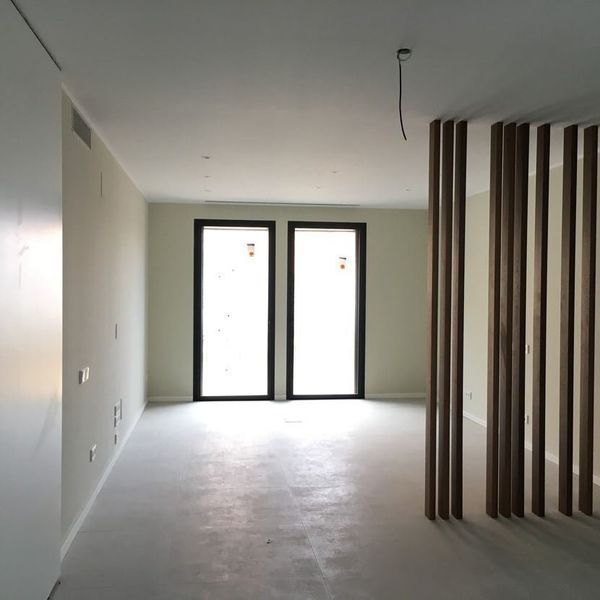 Una habitación vacía con dos ventanas y un divisor de madera.