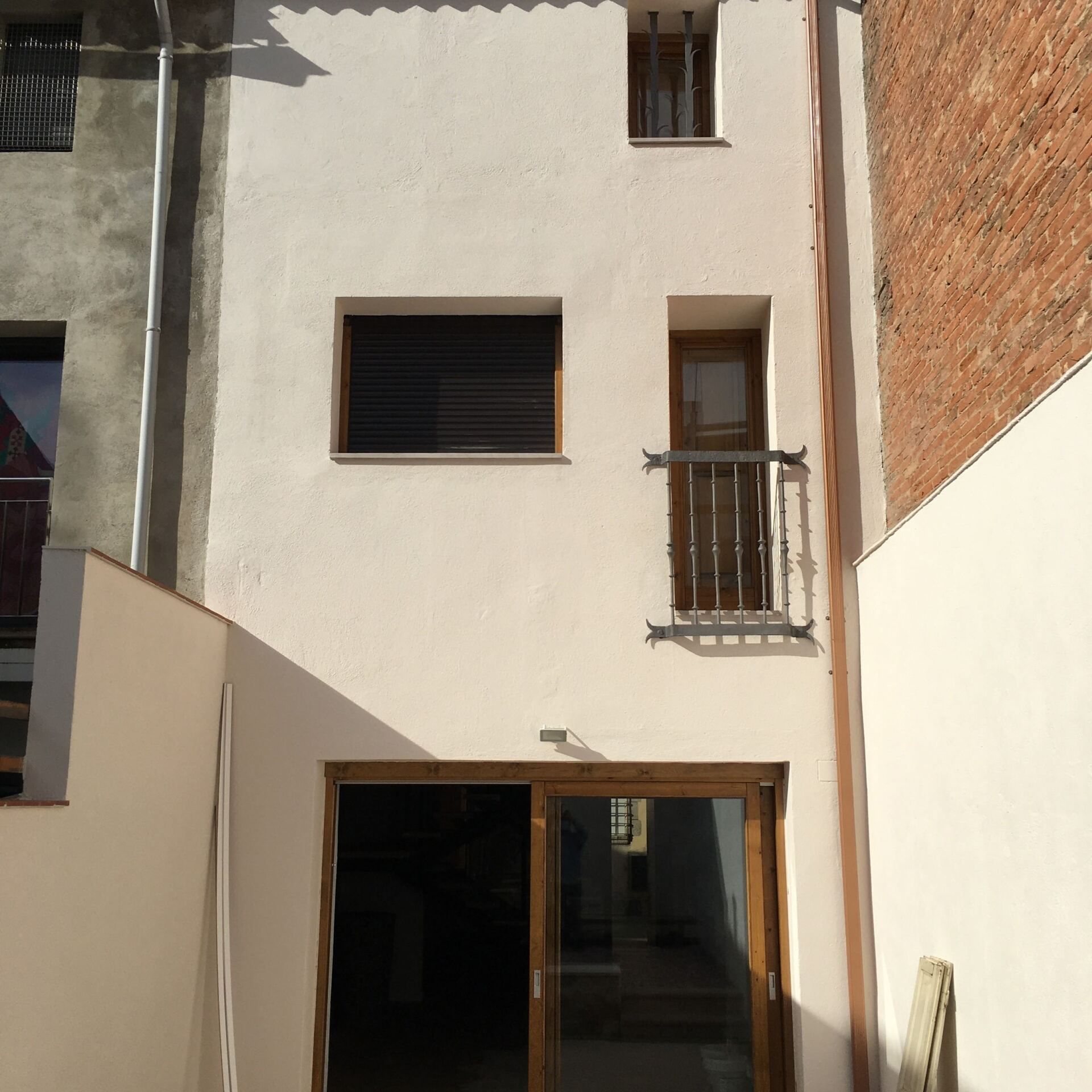 Un edificio blanco con balcón y puertas corredizas de vidrio.