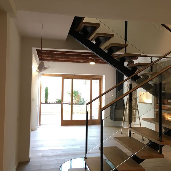 Una escalera con escalones de madera y barandilla de cristal.