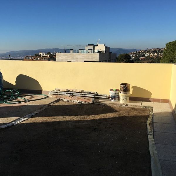 Un tejado con cubos de pintura y una manguera