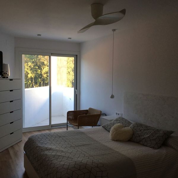 Un dormitorio con una cama, una silla y un ventilador de techo.