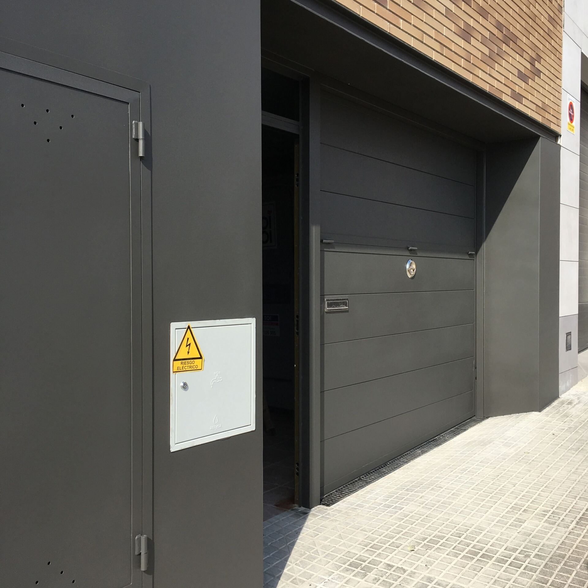 Una puerta de garaje negra con una señal de advertencia amarilla.