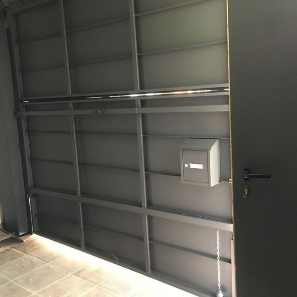 Una puerta de garaje con un buzón en la pared detrás de ella.