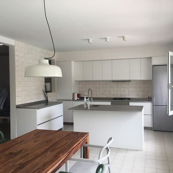 Una cocina con gabinetes blancos y una mesa de madera.