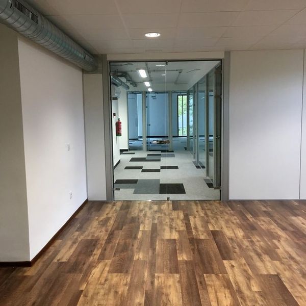 Un pasillo con suelos de madera y paredes blancas.