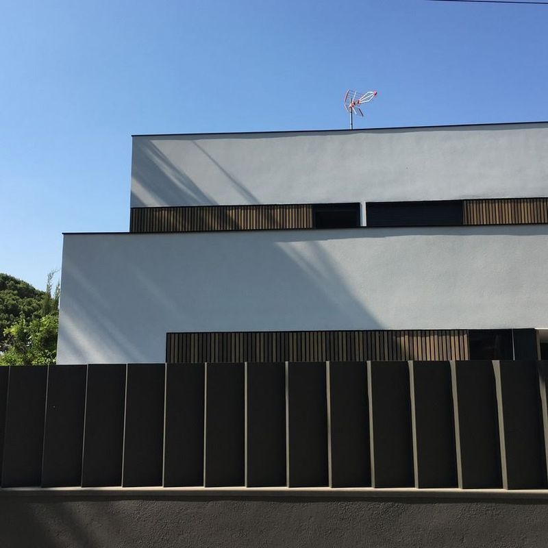 Un edificio blanco con una valla negra delante.