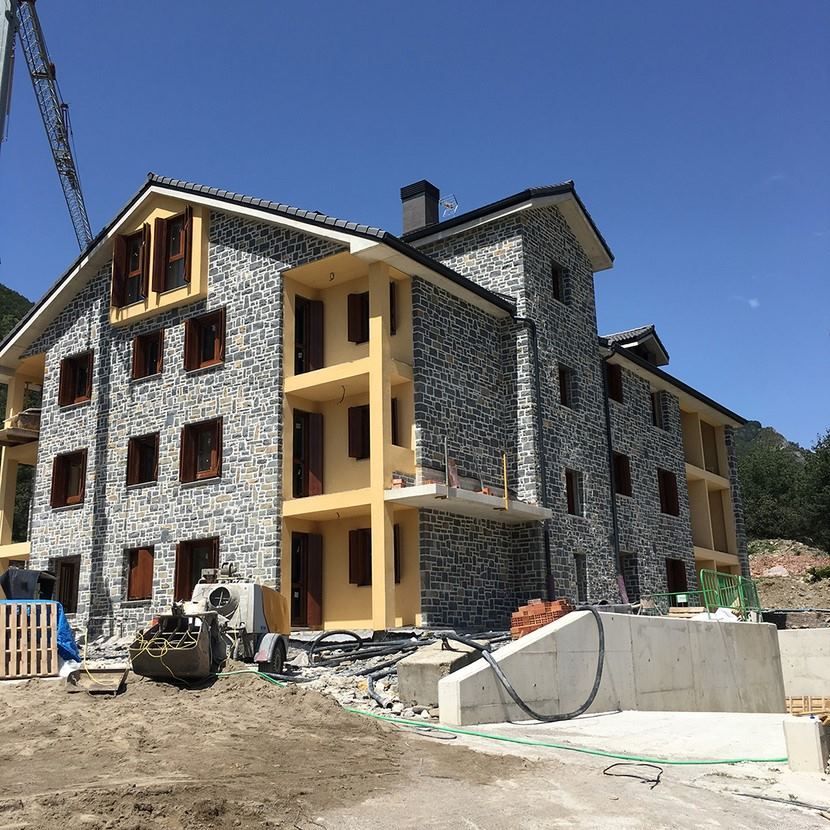 Se está construyendo un gran edificio de piedra con muchas ventanas.