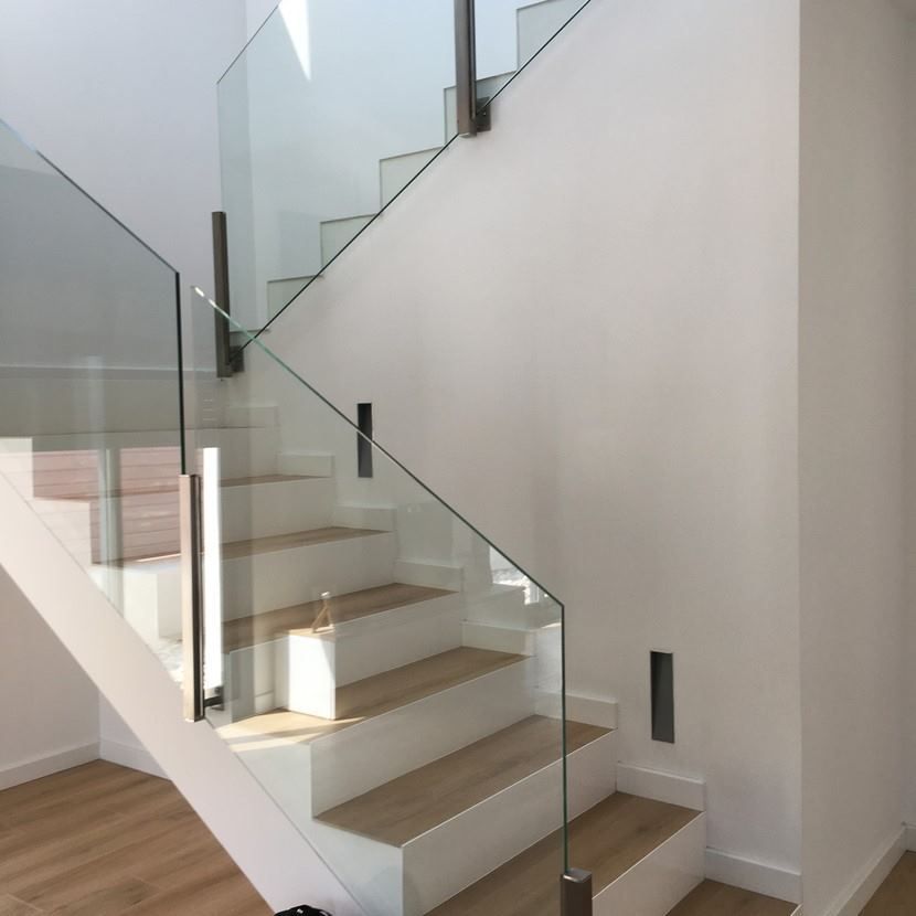 Una escalera con barandilla de cristal y escalones de madera.