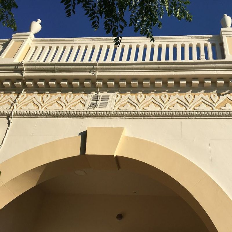 Un edificio con un balcón y un cielo azul al fondo.