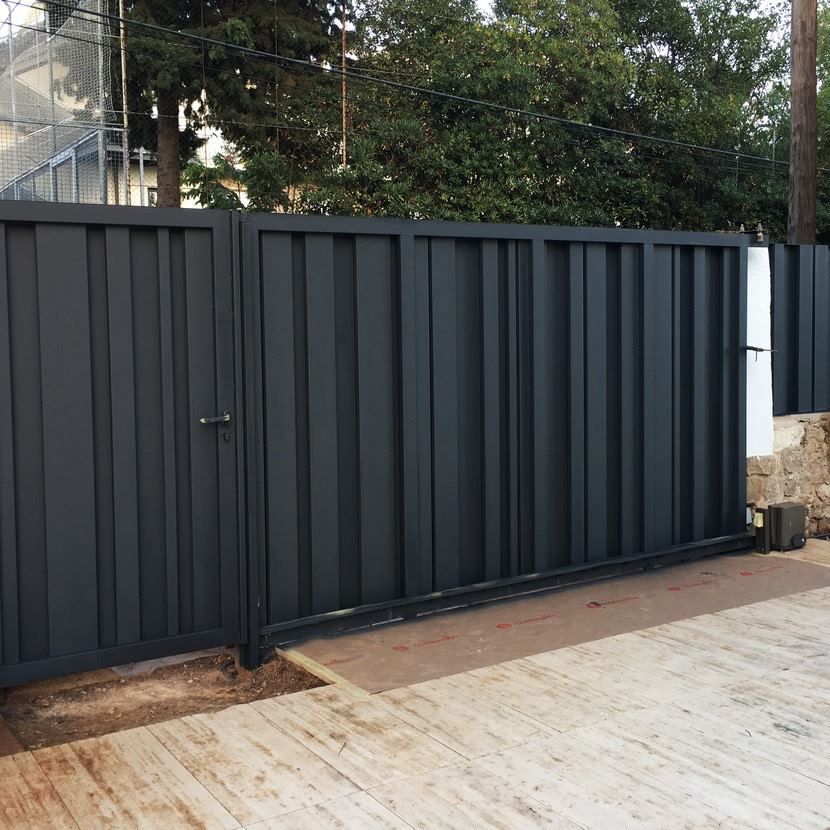 Una valla negra con una pasarela de madera delante de ella.