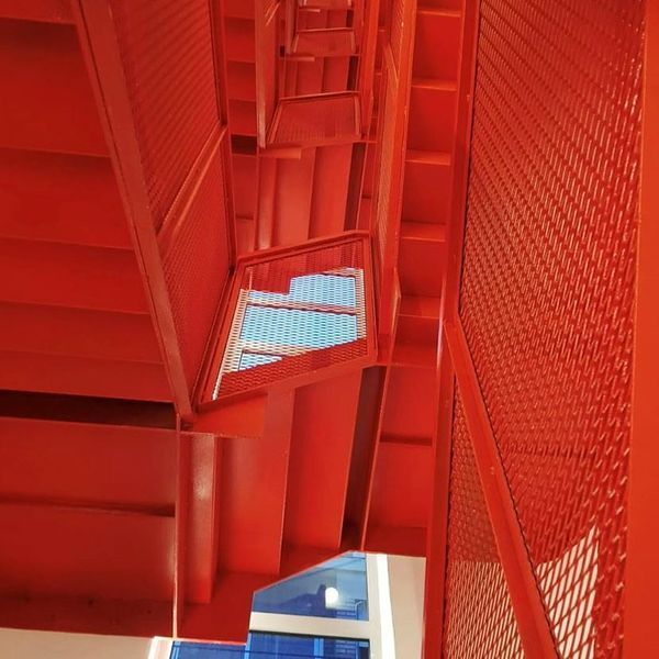 Una escalera roja con un cielo azul al fondo.