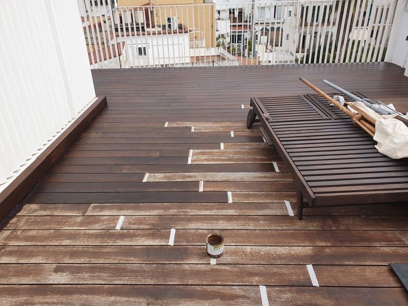 Una terraza de madera con una silla y una taza encima.