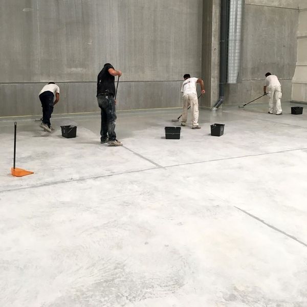 Un grupo de hombres está limpiando un piso de concreto.