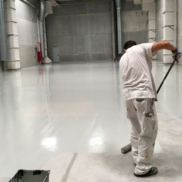 Un hombre está pintando un piso con un rodillo.