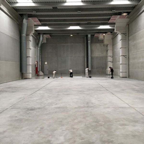 Un grupo de personas está trabajando en un gran almacén vacío.