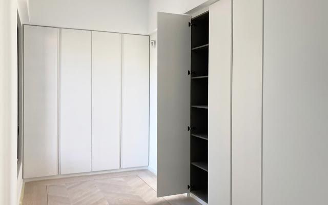 Una habitación con paredes blancas y un armario con la puerta abierta.
