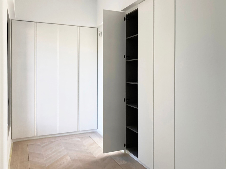 Una habitación con muebles blancos y un armario con la puerta abierta.