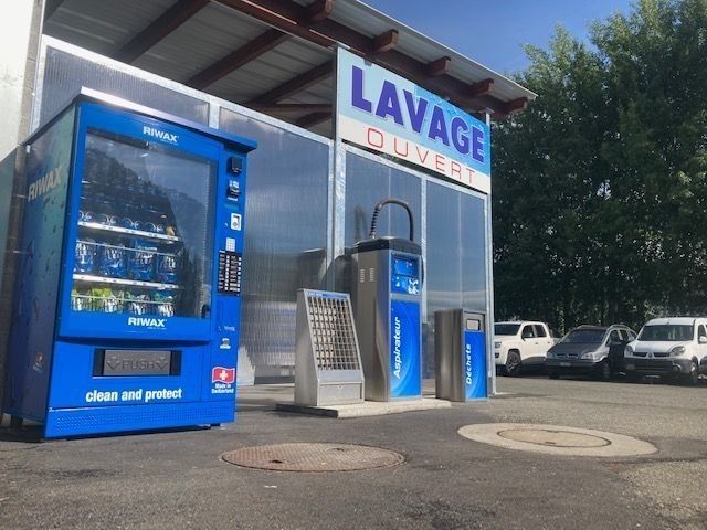 Station de lavage auto bleue avec bornes de paiement et panneau « LAVAGE » à l'extérieur