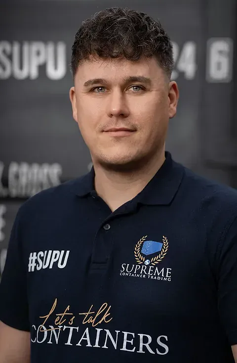 Mann in dunkelblauem Poloshirt mit der Aufschrift „Supreme Container Solutions“ blickt in die Kamera. Dunkler Hintergrund.