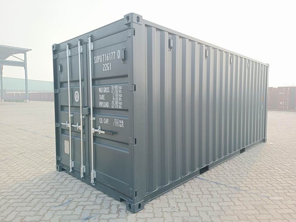 Grauer Schiffscontainer auf einer gepflasterten Fläche.