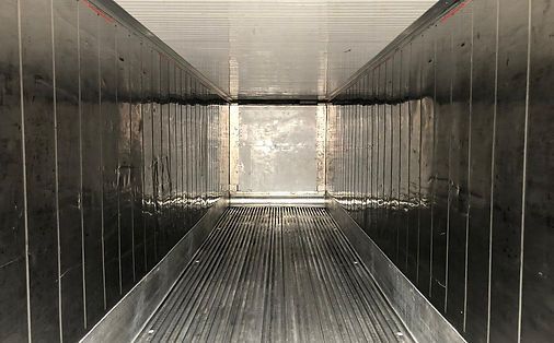 Innenansicht eines Kühlaufliegers, Metallwände mit vertikalen Rillen, leer und lichtreflektierend.