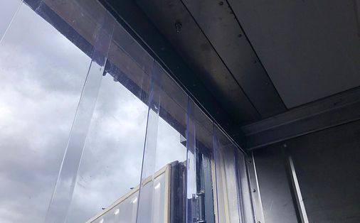 Ein durchsichtiger Kunststoffstreifenvorhang hängt von der Decke und bildet eine Barriere.