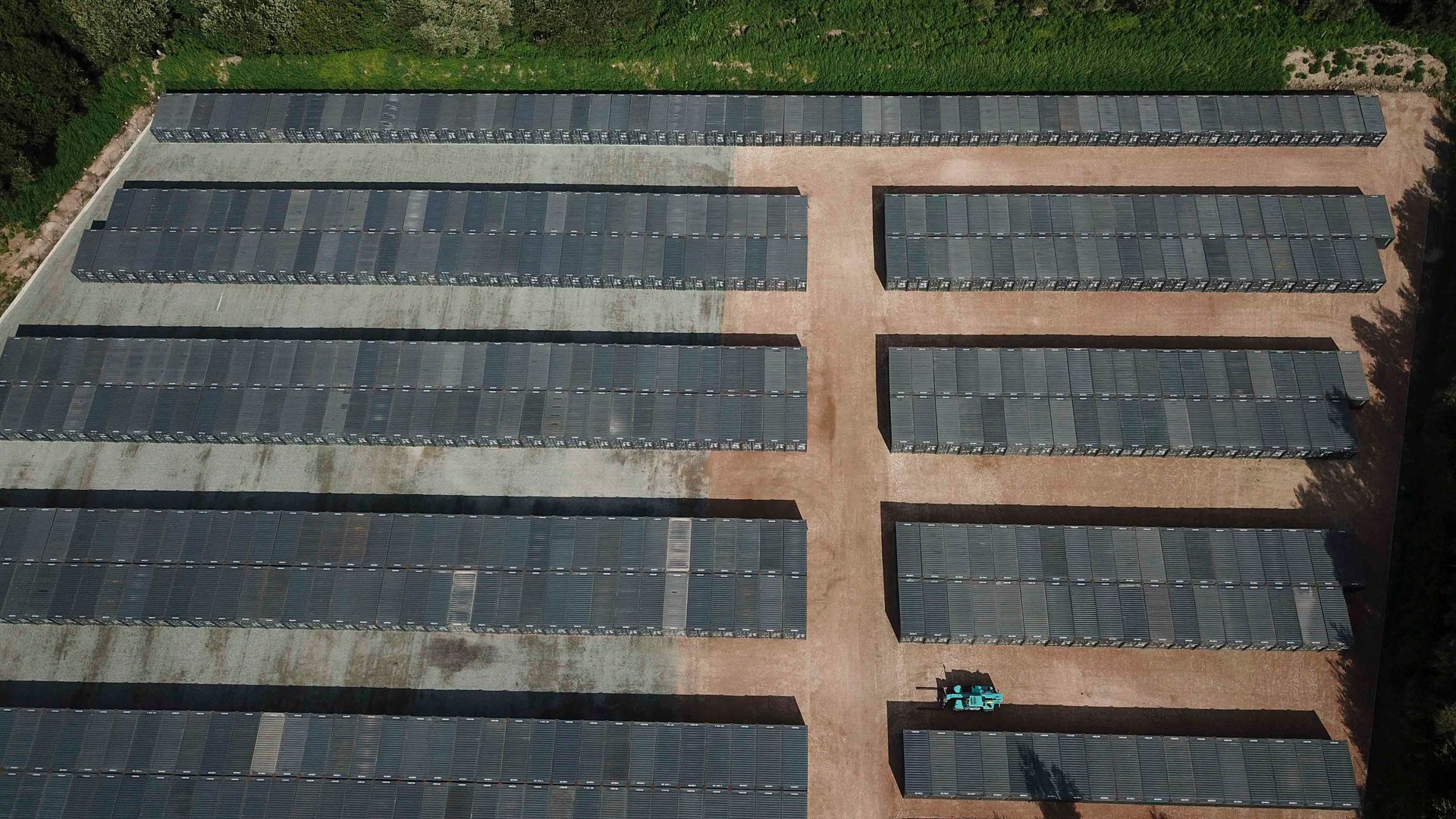 Luftaufnahme einer Solarmodulanlage auf einem Feld, die Module sind in Reihen angeordnet.