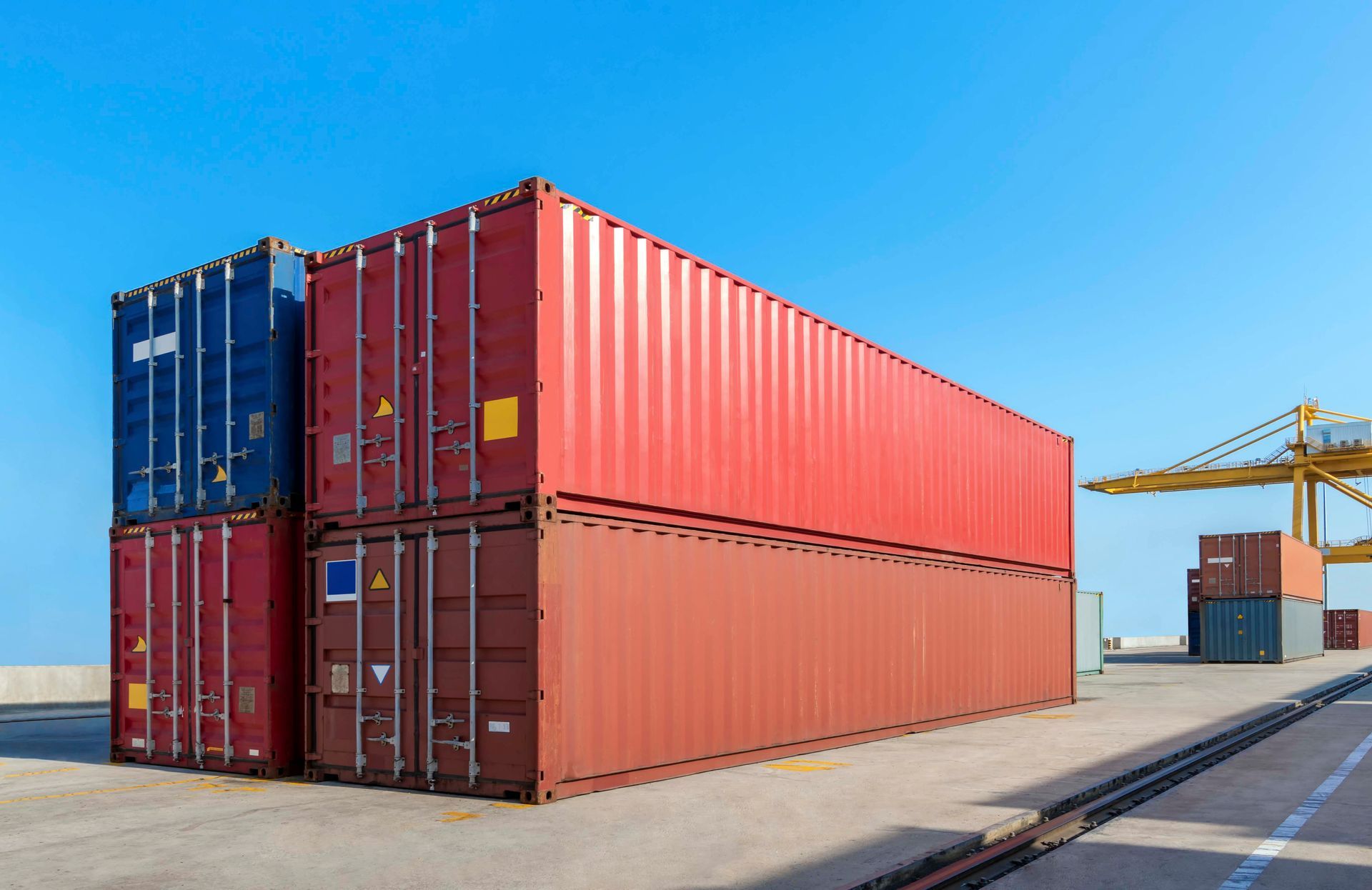 Im Hafen vor blauem Himmel stapeln sich Schiffscontainer.