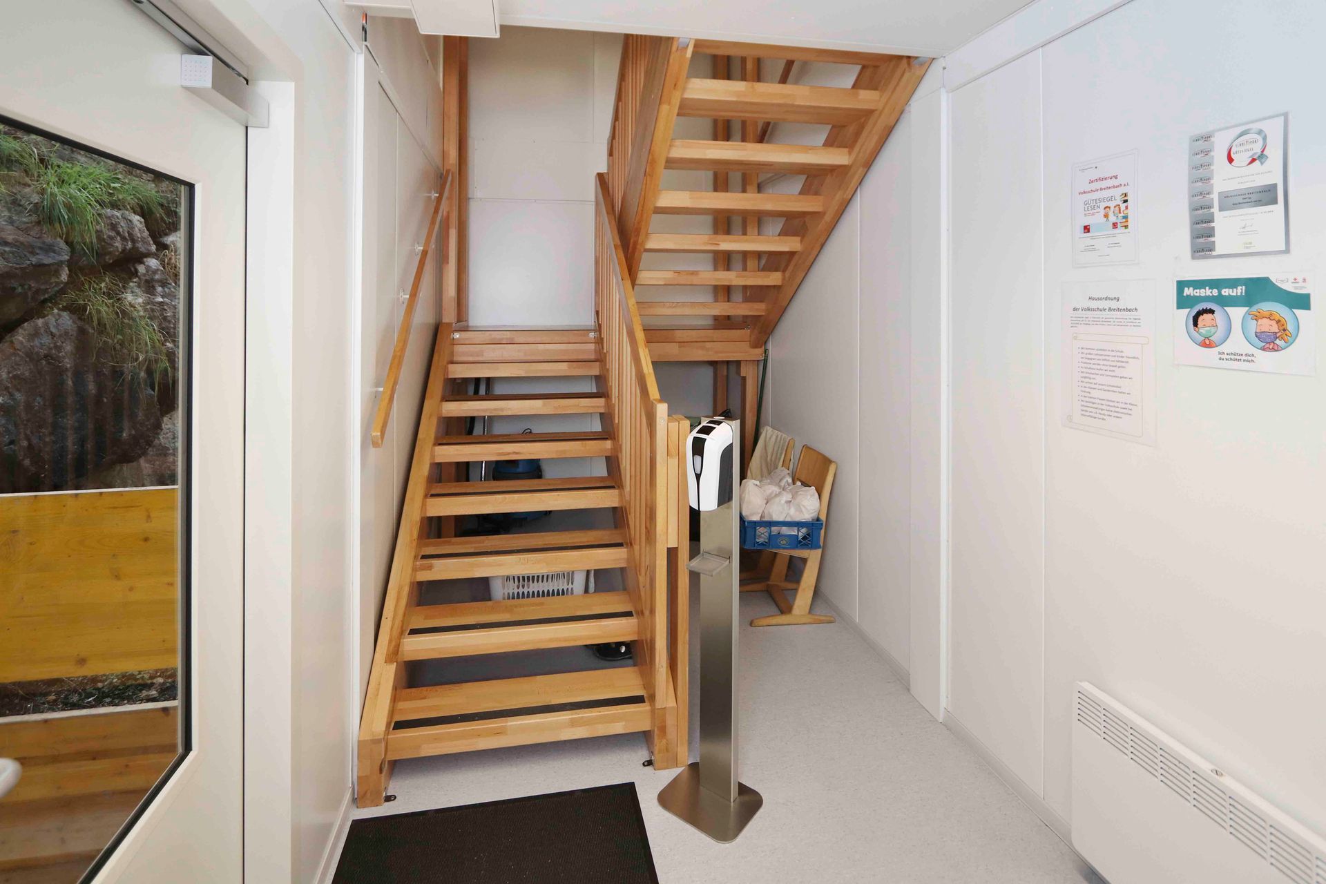 Innenraum eines leeren Schiffscontainers mit weißen Wänden, schwarzem Boden und einem Schaltschrank auf der rechten Seite.