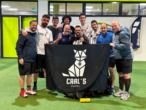 Un grupo de hombres posa para una foto con una bandera de Carl's Padel.